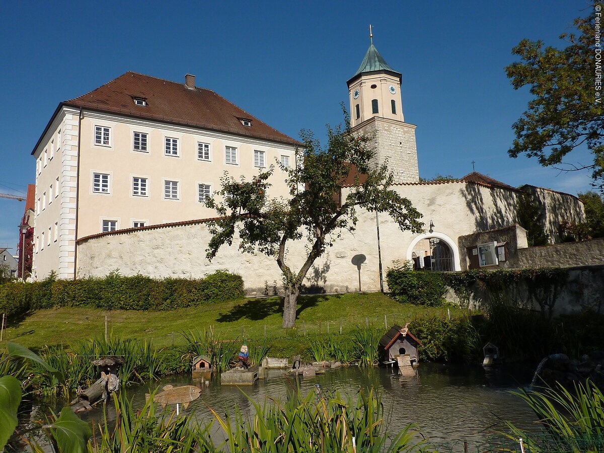 Ehemalige Schloss Gosheim mit Weiher und Pfarrkirche Mariä Geburt Blick auf das ehemalige Schloss Gosheim mit davor liegendem Weiher. Rechts neben dem Schloss sieht man den Turm der Pfarrkirche Mariä Geburt.