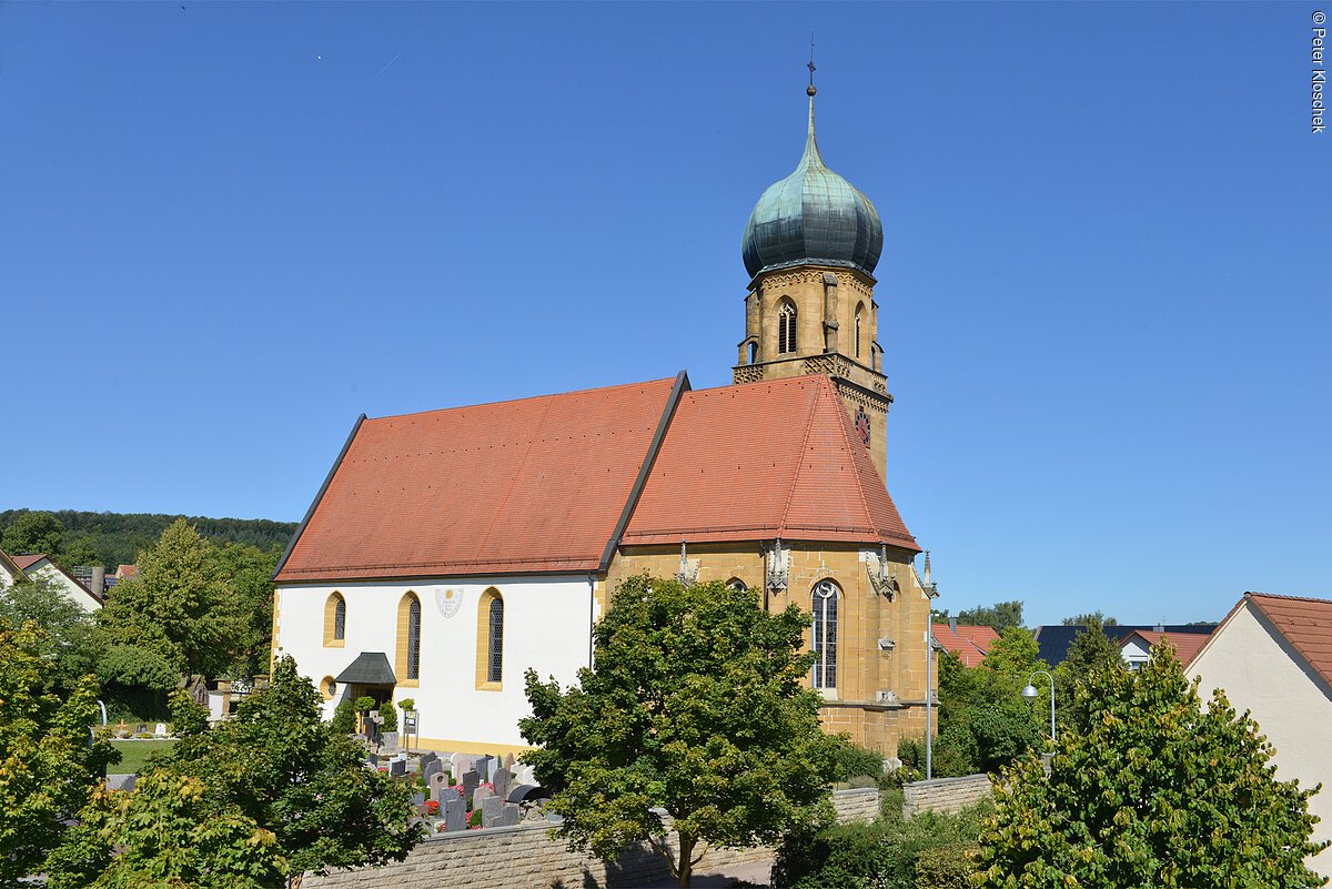 Blick auf die teils von Bäumen verdeckte Pfarrkirche St. Gangolf.