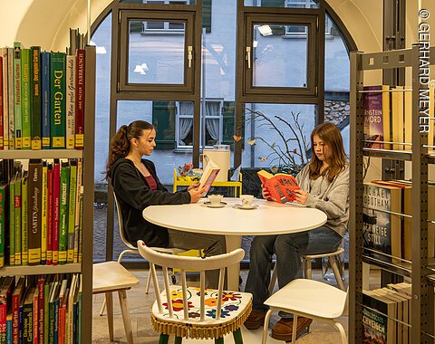 Zwei Mädchen lesen im Lesebereich der Bücherei