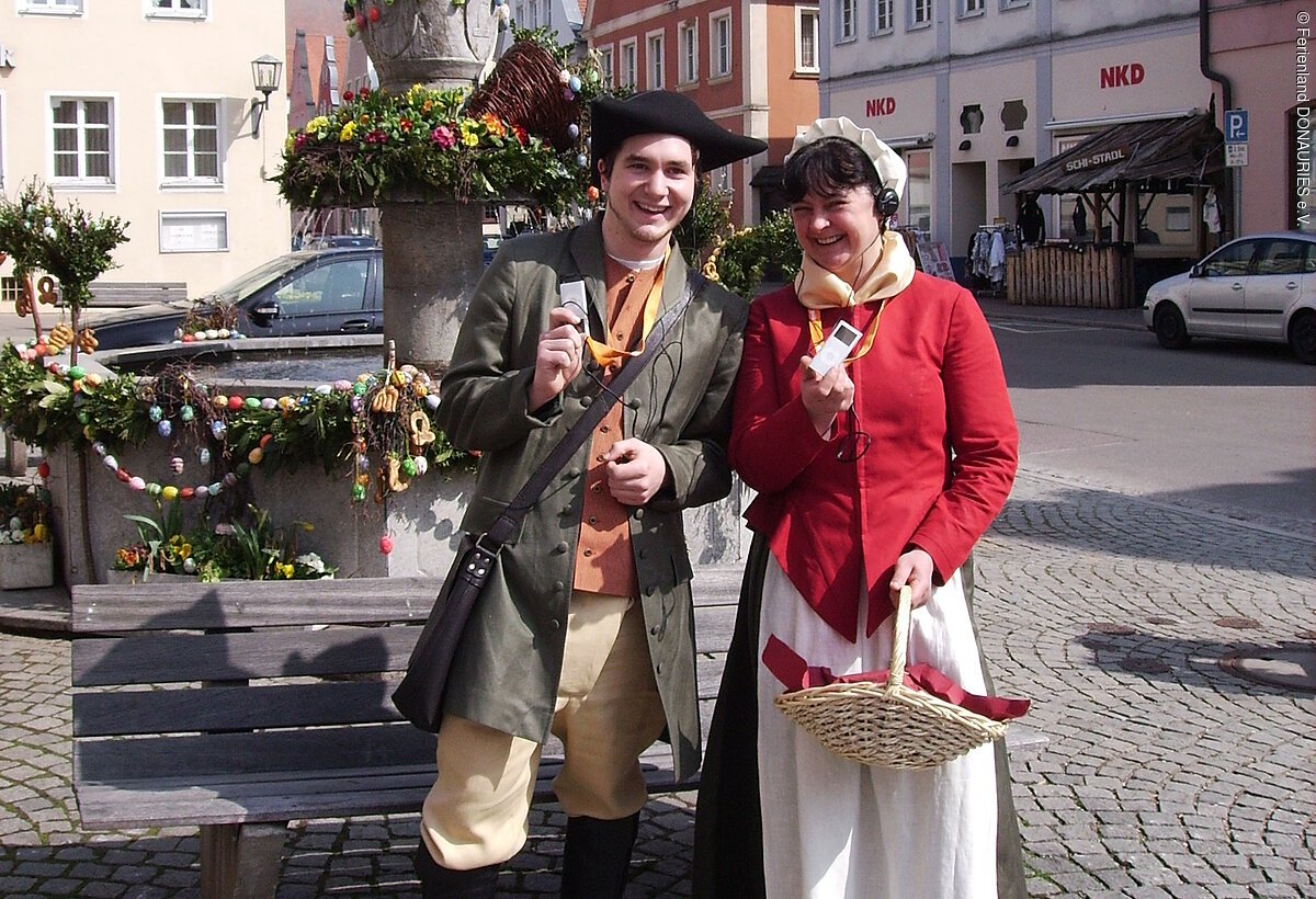 Die Lebküchnerin Frau Stahl und Perückenmachergeselle Jakob vor dem Brunnen am Marktplatz
