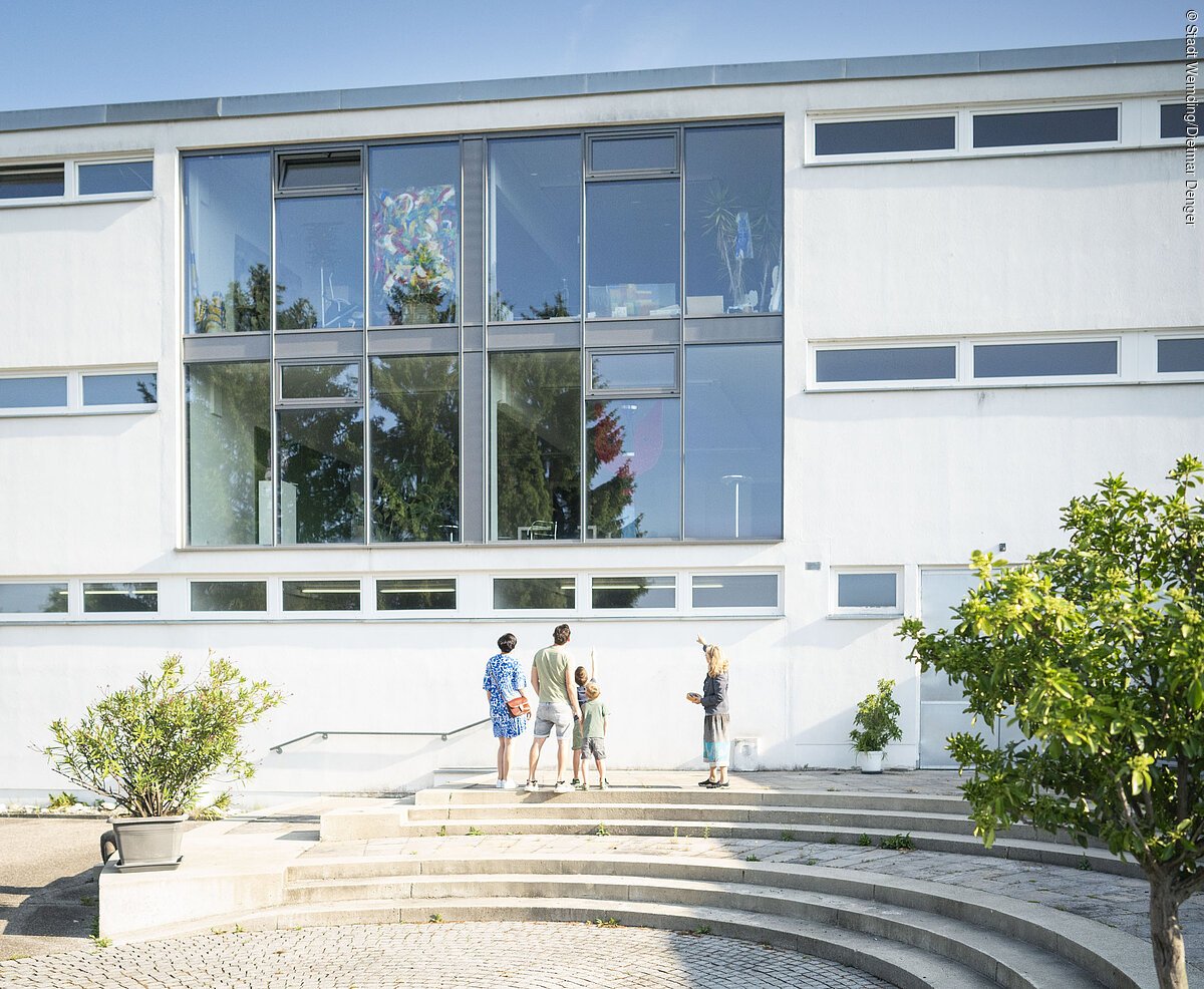 Die Leiterin des KunstMuseums zeigt das Museum von außen und führt es einer Gruppe vor.