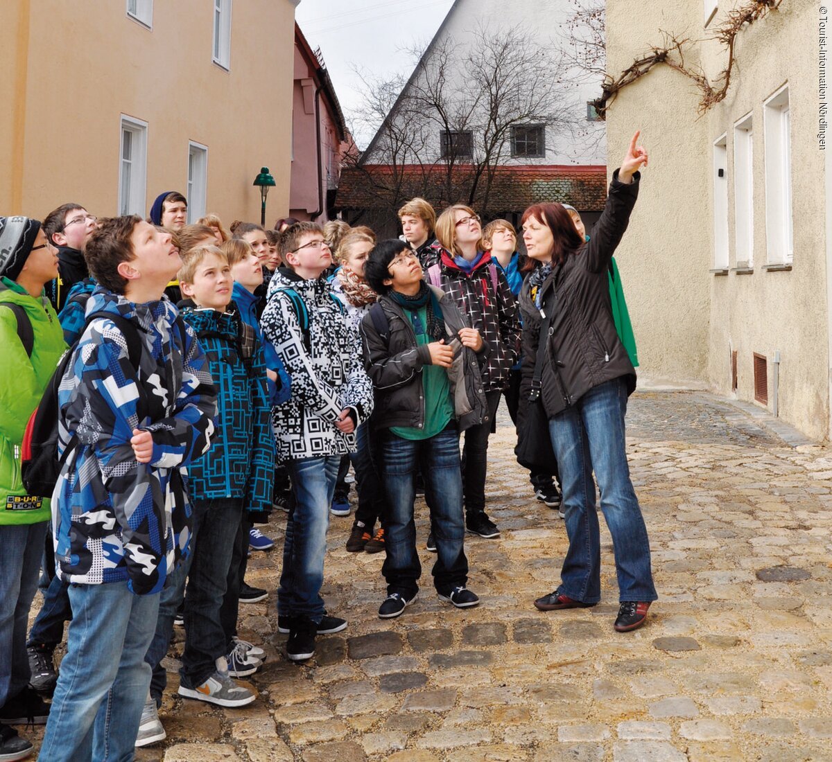 Eine Führerin erklärt interessierten Kinder etwas  in der Altstadt von Nördlingen.