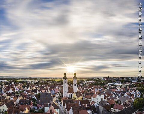 Wemding und Donau-Ries Panoramablick auf Stadt mit roten Dächern und zwei Kirchtürmen bei Sonnenuntergang unter bewölktem Himmel