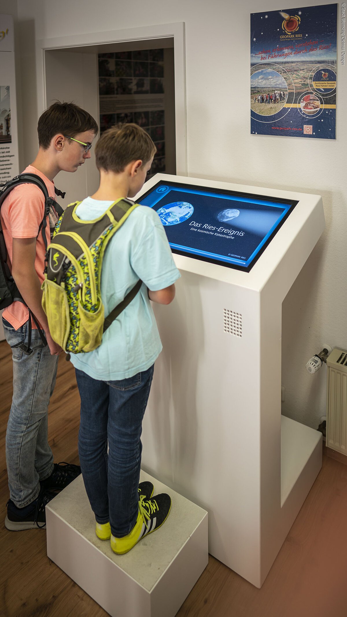 Kinder schauen sich die Ries-Animation in der Geopark-Infostelle an.