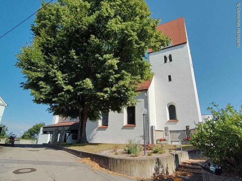 Kirche Münster Kirche der Gemeinde Münster. Ein schlichter romanischer weißer Kirchenbau mit Baum davor.